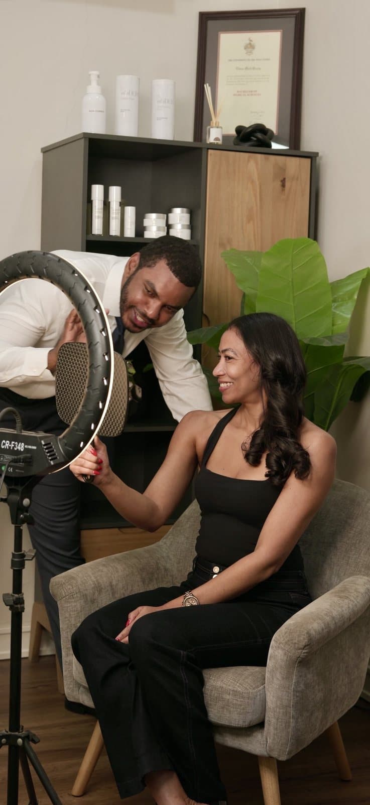 A client looks in a hand mirror while Dr. Breedy stands beside her